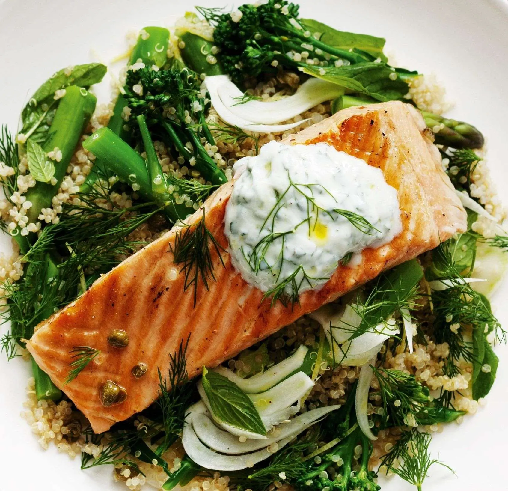 Grilled salmon served over a bed of couscous, greens and ...