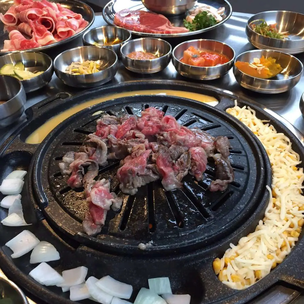 Korean BBQ grill accompanied by side dishes. Outer grill had some sort ...